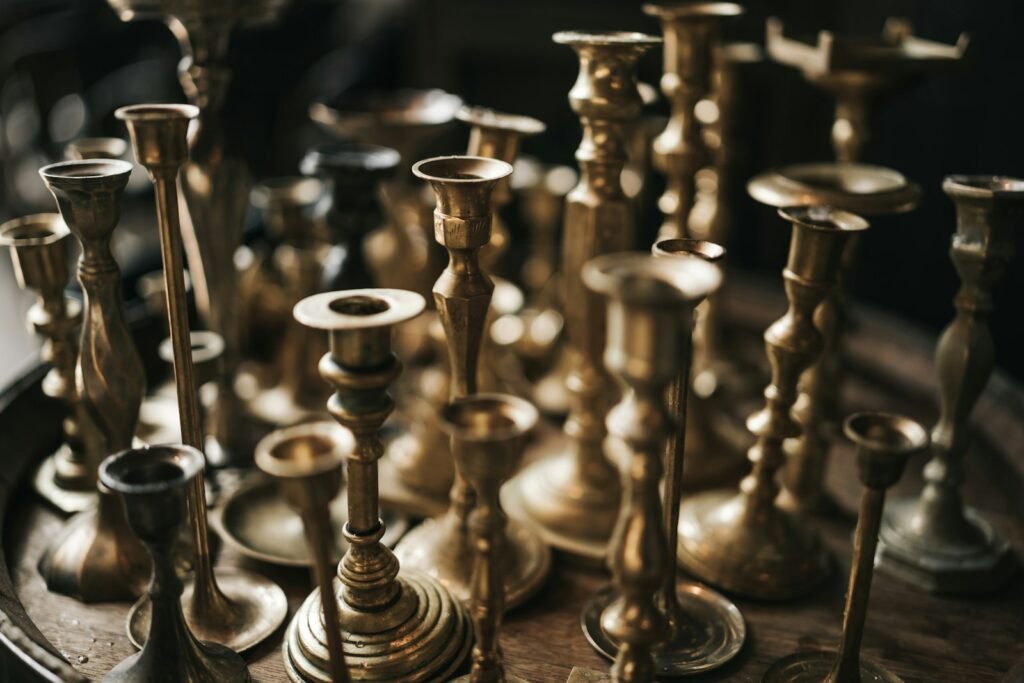 Collection of thrifted brass candlesticks and vintage decor on a shelf