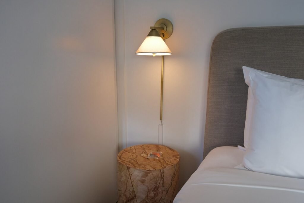 Renter-friendly bedroom with plug-in wall sconce and removable decor above the bed