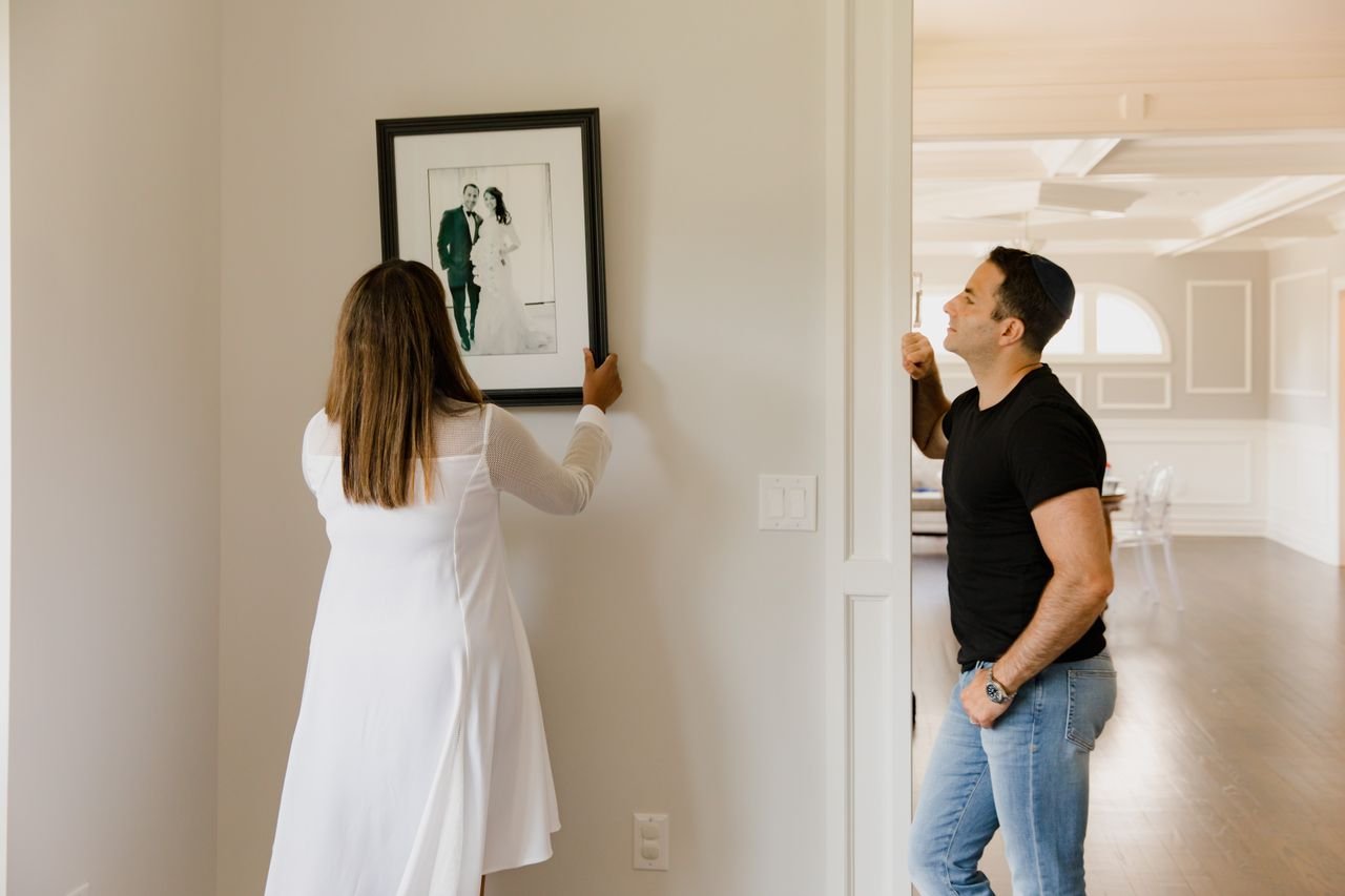 Couple hanging framed art on an apartment wall without damage