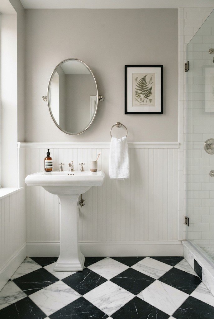 Black and white checkerboard floor in a vintage-style bathroom with a pedestal sink
