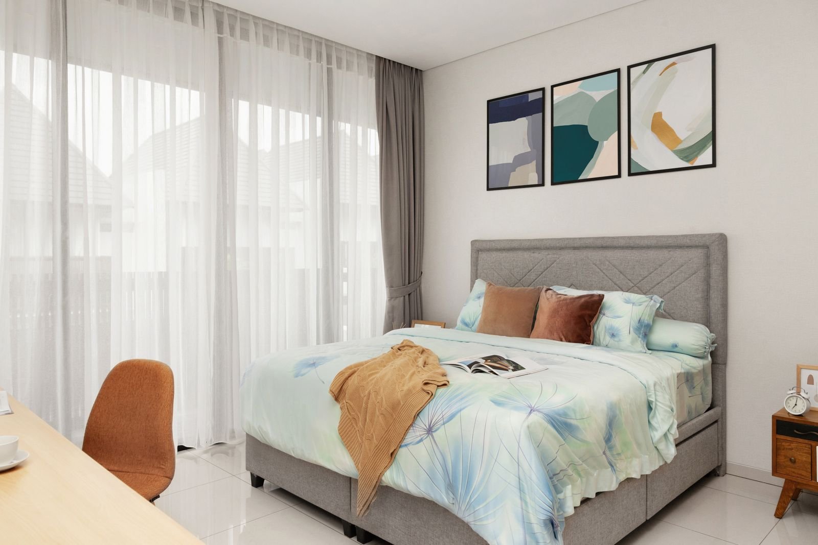 Bedroom with framed art above the bed and soft curtains