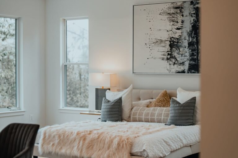 Cozy small apartment bedroom with window light, bedside lamp and framed art