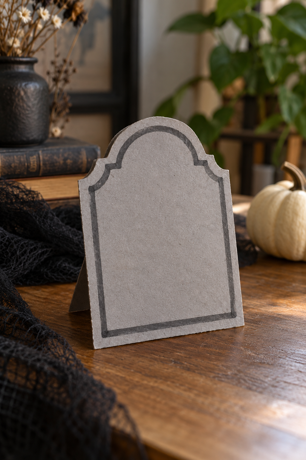 Miniature gray cardboard tombstone with a decorative border