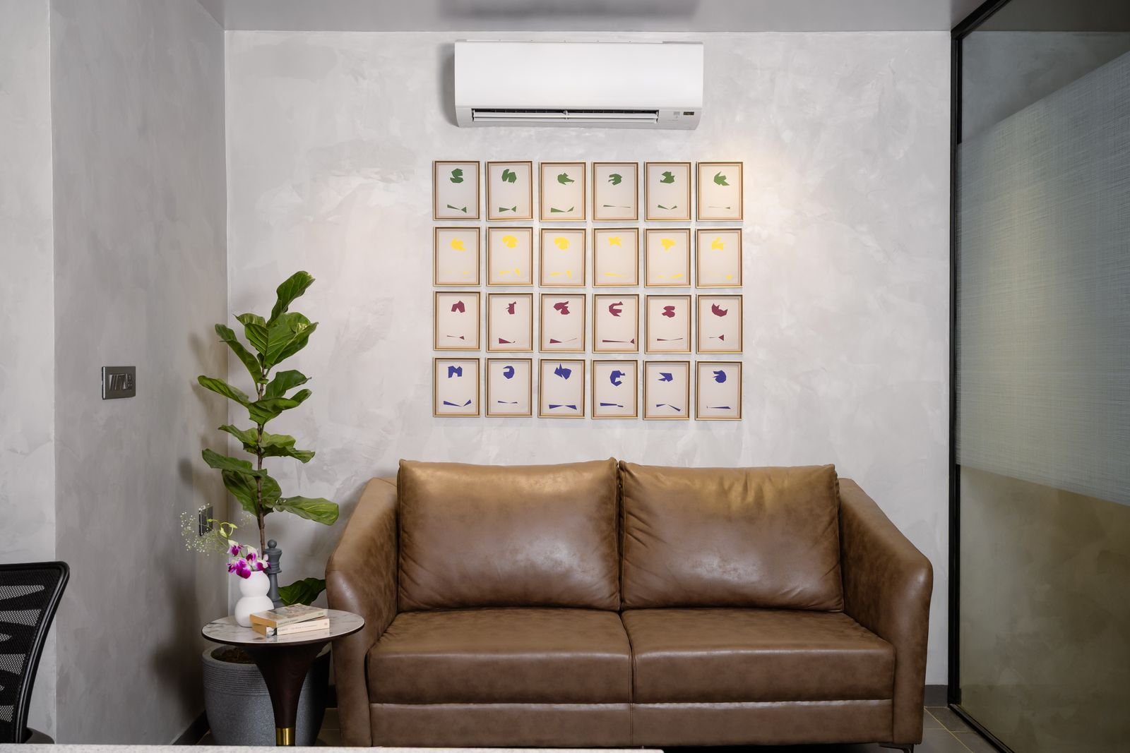 Grid gallery wall above a leather sofa in a small living room