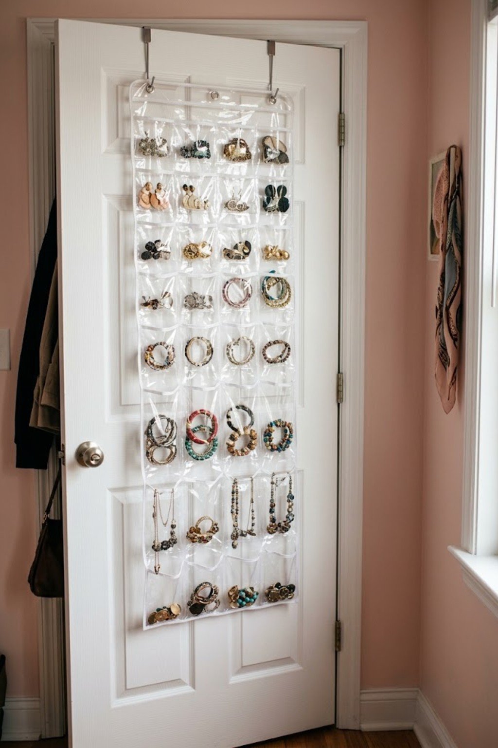 Clear jewelry organizer with earrings and necklaces on a bedroom door