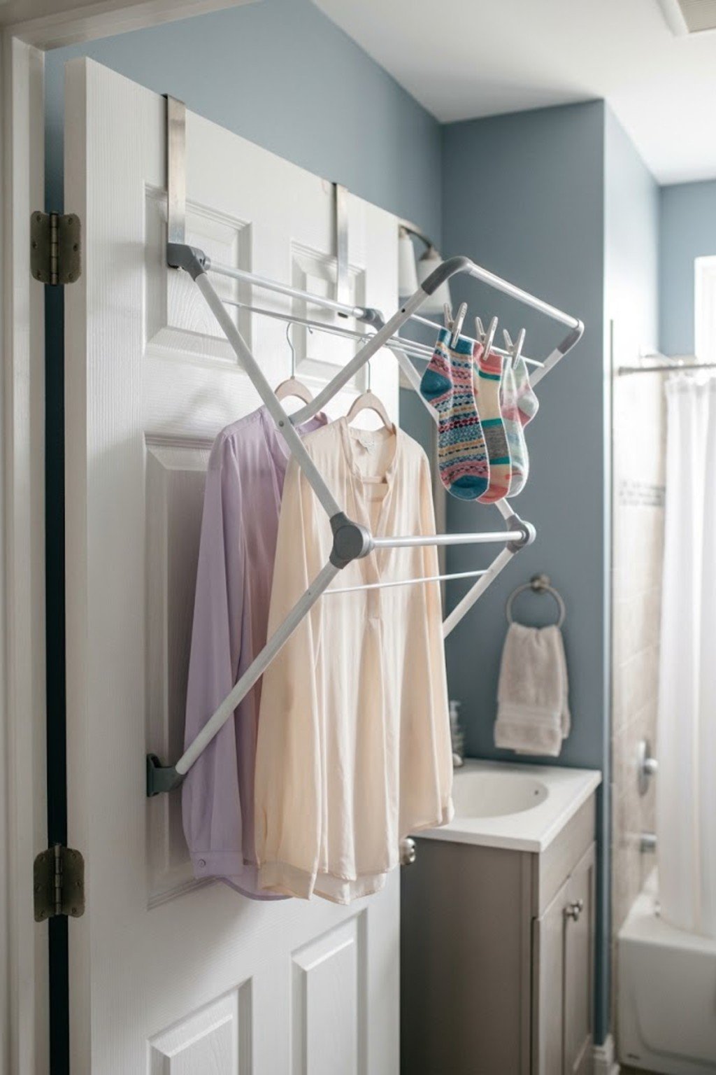 Over-the-door drying rack holding delicate clothes on a bathroom door