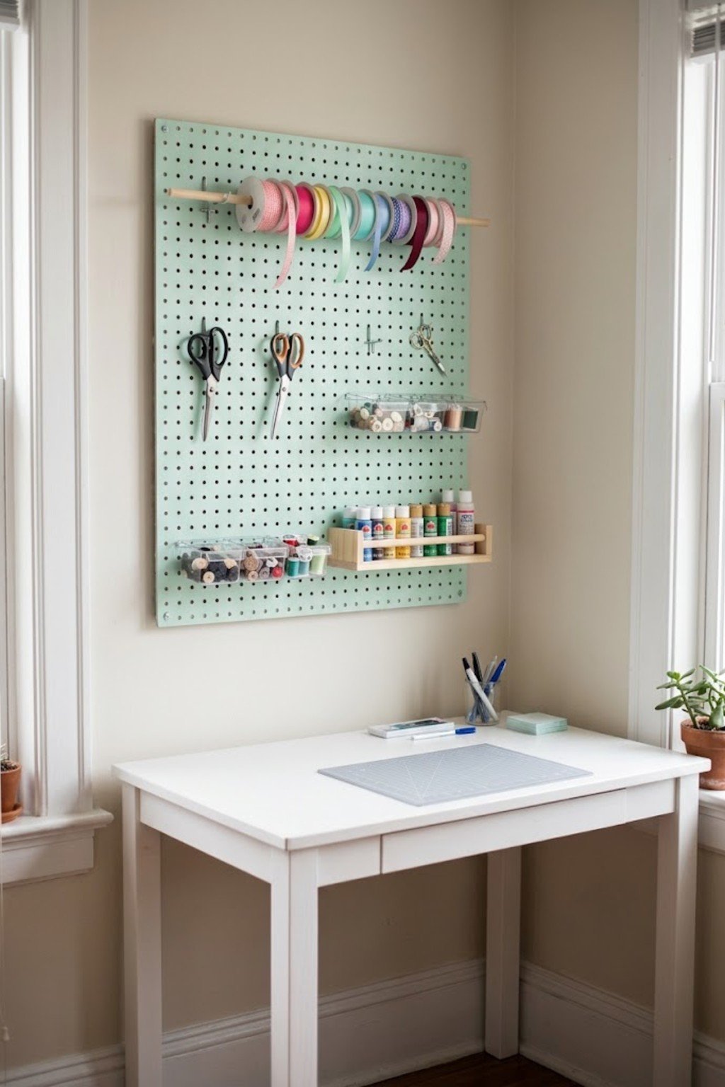 Mint pegboard craft wall with ribbon, scissors and small bins