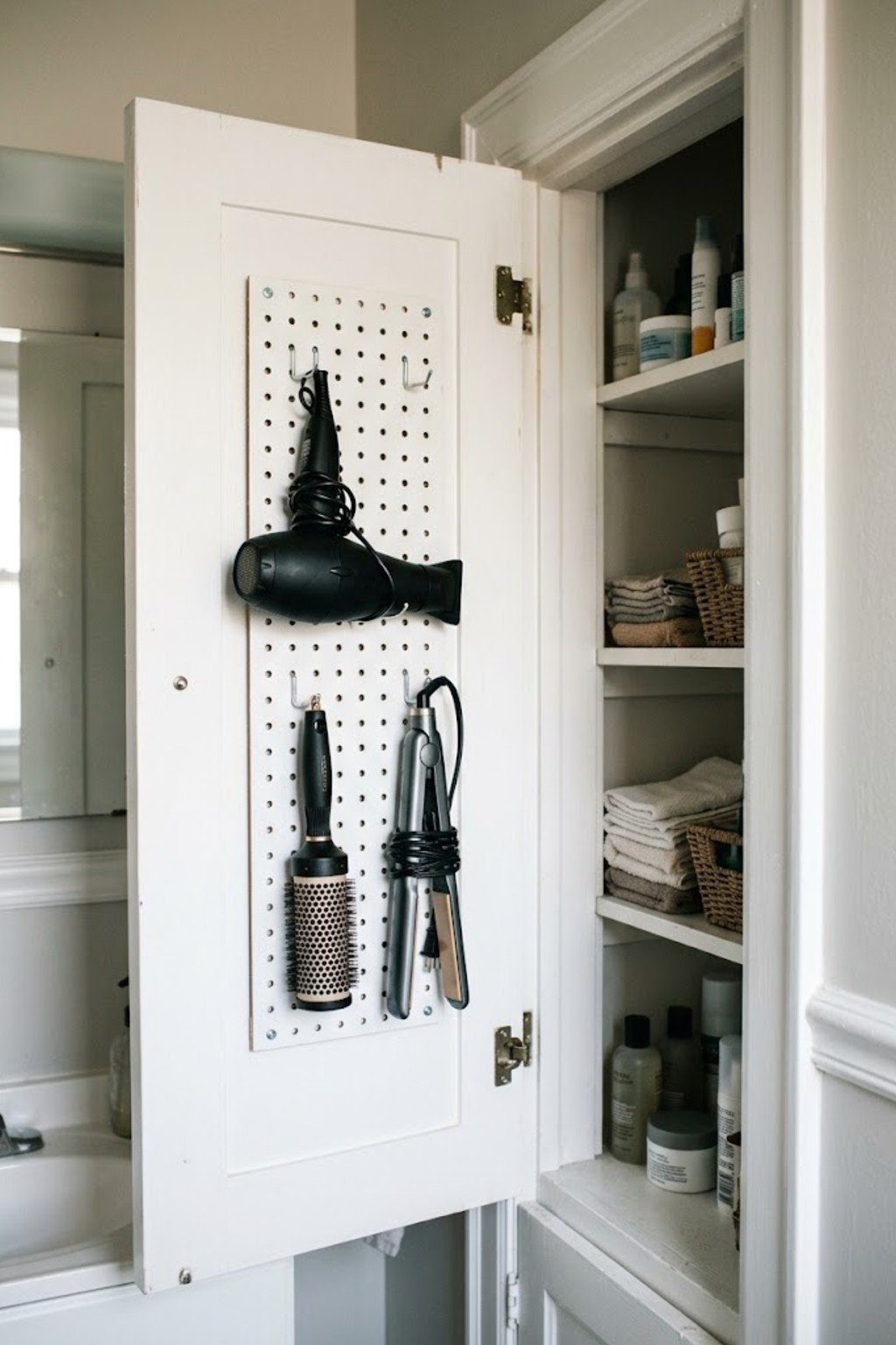 Pegboard inside a cabinet door holding hair tools