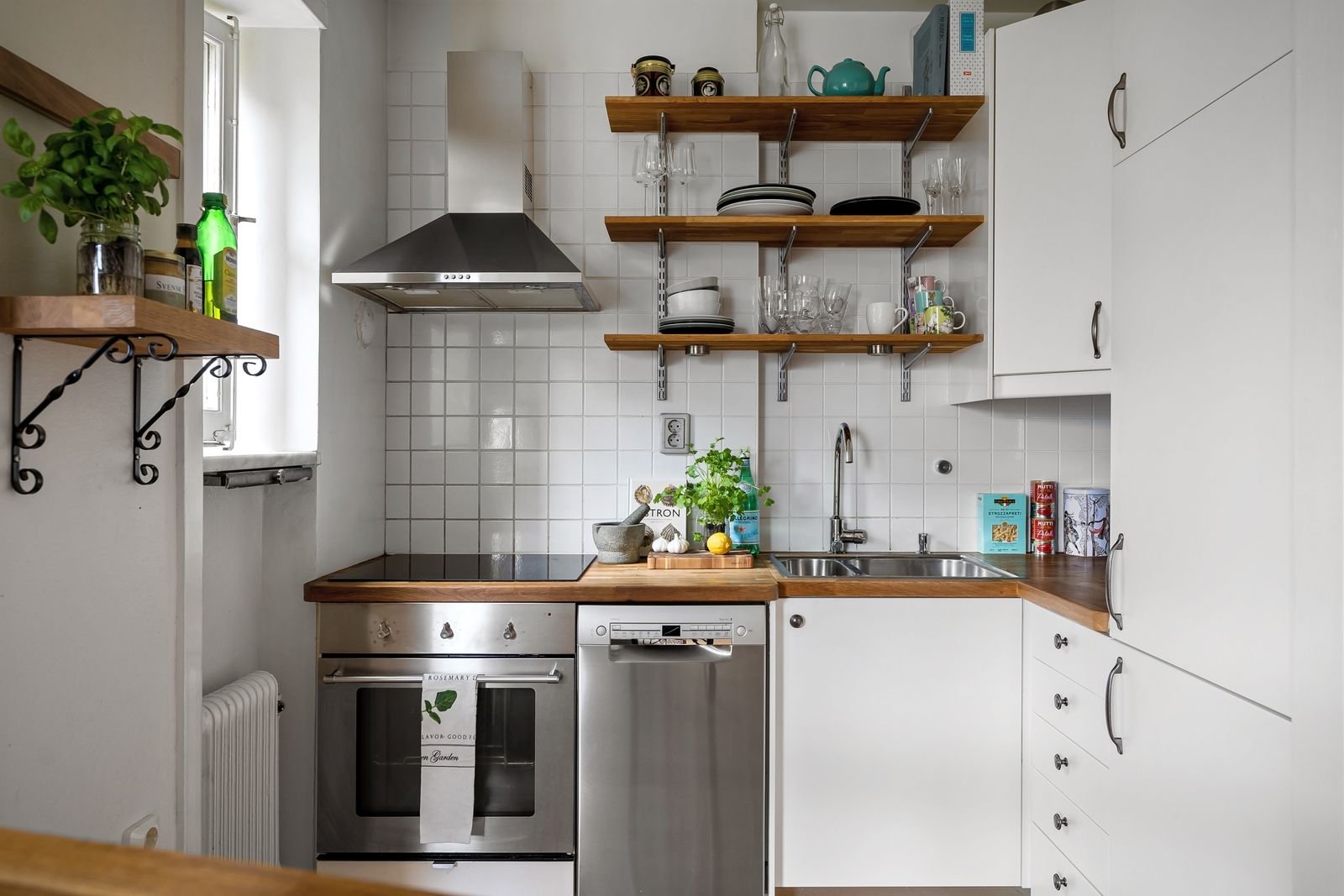 Simple white rental kitchen with open wood shelves and plants