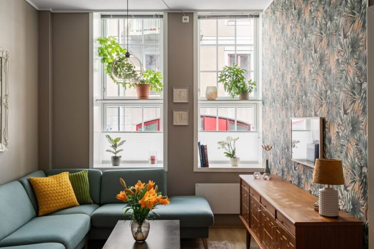 Small apartment living room with a teal sofa, plants and natural light