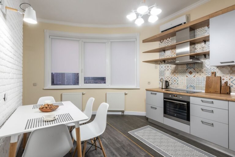 Small white rental kitchen with a simple dining table and patterned tile
