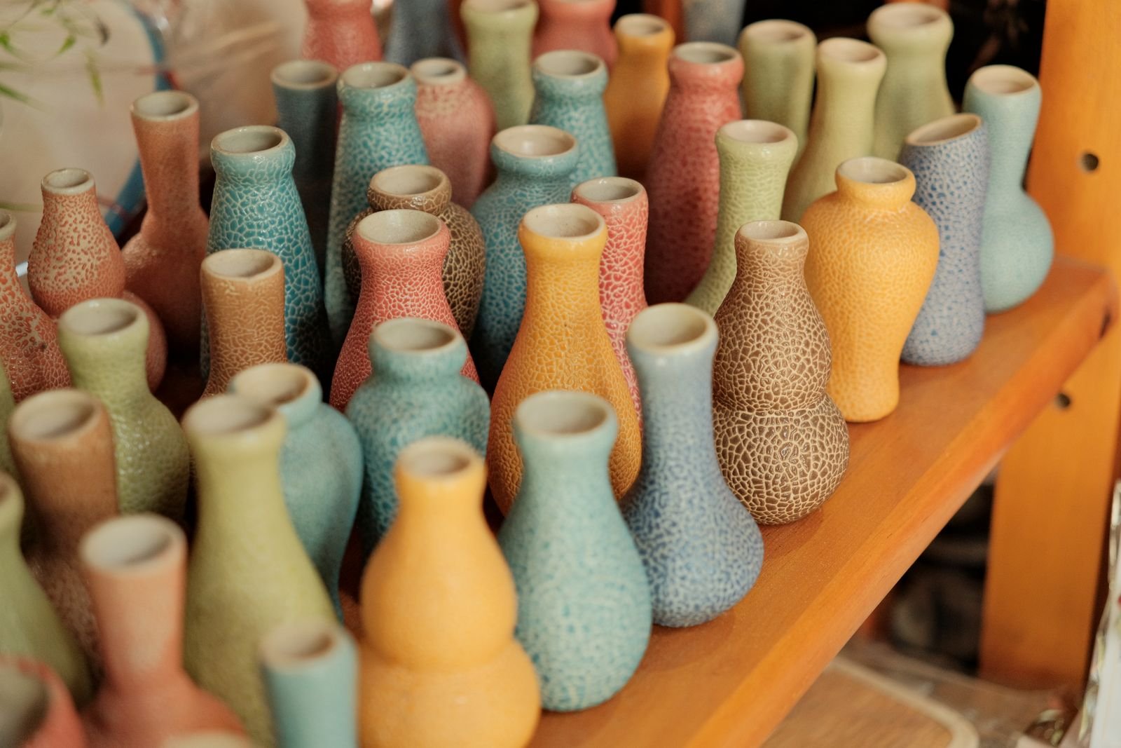 Shelf of colorful secondhand ceramic vases at a thrift store